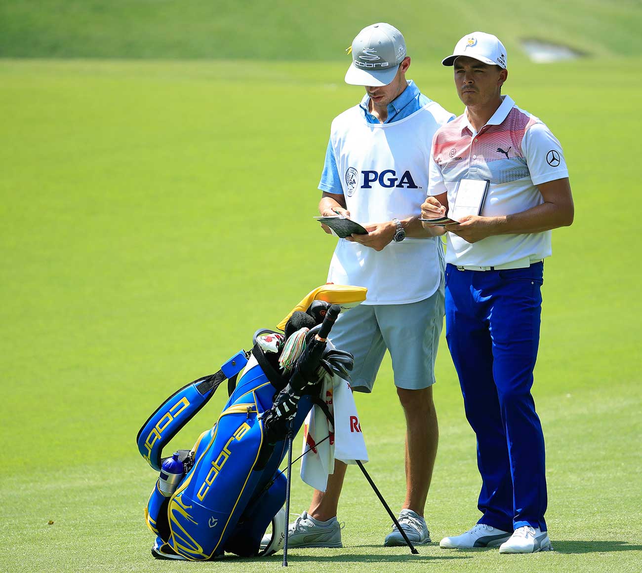 Rickie Fowler and caddie talk over a shot.