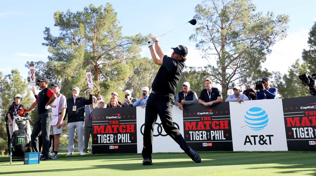 Phil Mickelson tees off during The Match as Tiger Woods looks on.